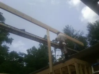 Carpenter setting a ridge beam over a new addition frame — Ice Dam Removal by Roofing Brothers in Royalston