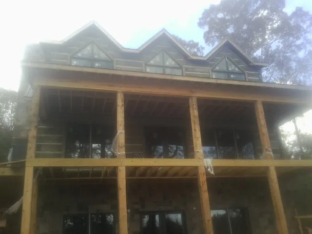 Dormers and porch framing on a large log home under construction — Roof Coating work by our crew in Royalston