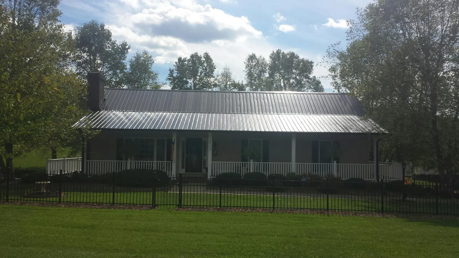 Gray metal roof on a brick ranch with a full width front porch — Gutter Guard Installation work by our crew in Royalston