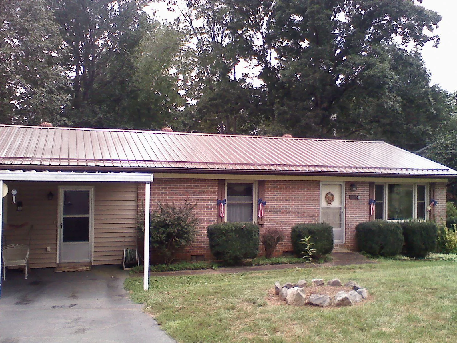 Bronze metal roof and carport on a brick ranch home — Roof Repair work by our crew in Royalston