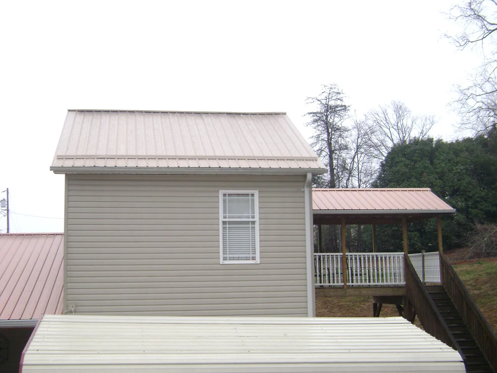 Tan metal roofs on a two story addition and attached porch, from a Roof Replacement job in Royalston
