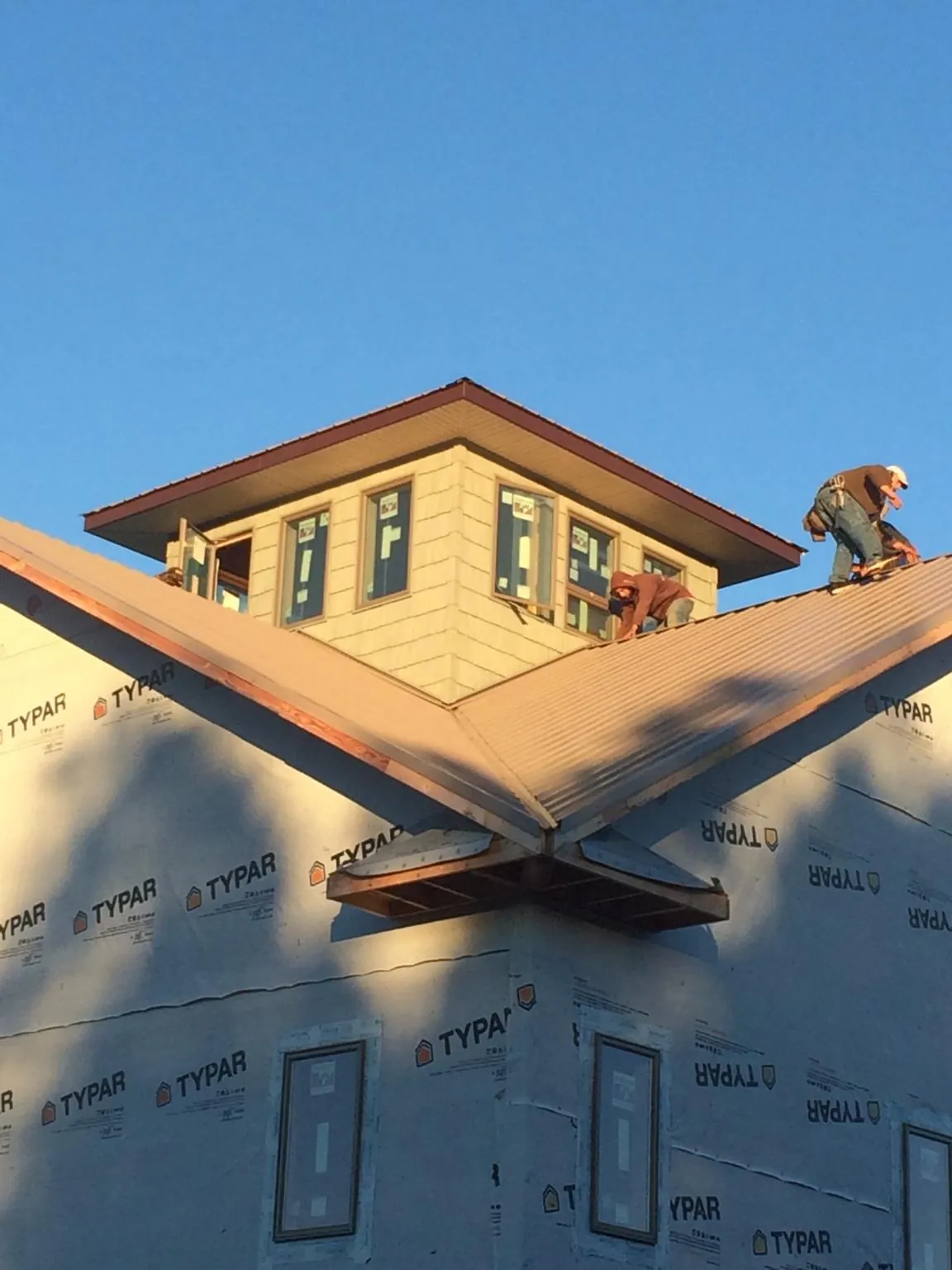Roofers working around a rooftop cupola on a new metal roof at sunset — Roof Waterproofing in Royalston by Roofing Brothers